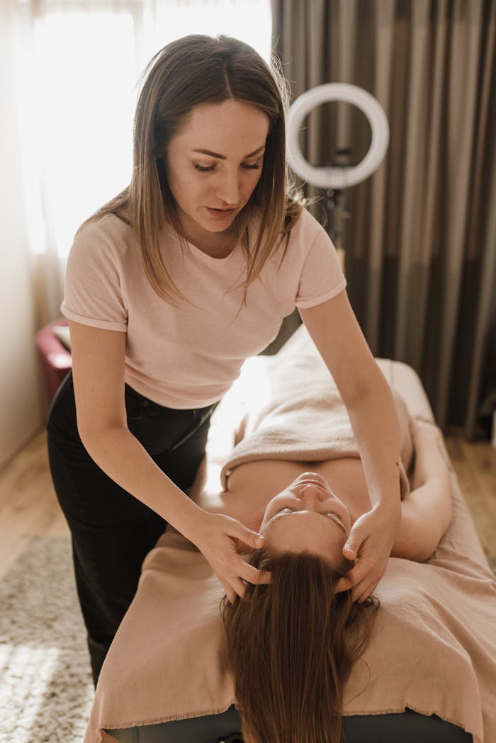 A masseuse provides a soothing head massage to a client at an indoor spa, enhancing relaxation.